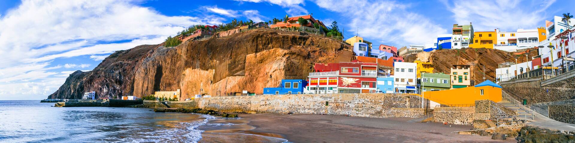 Spain Gran Canaria Puerto de Sardina high resolution 11K panorama of coastal village. Colorful houses on volcanic black sand beach with ochre cliffs. Scenic Canary Islands travel wall art