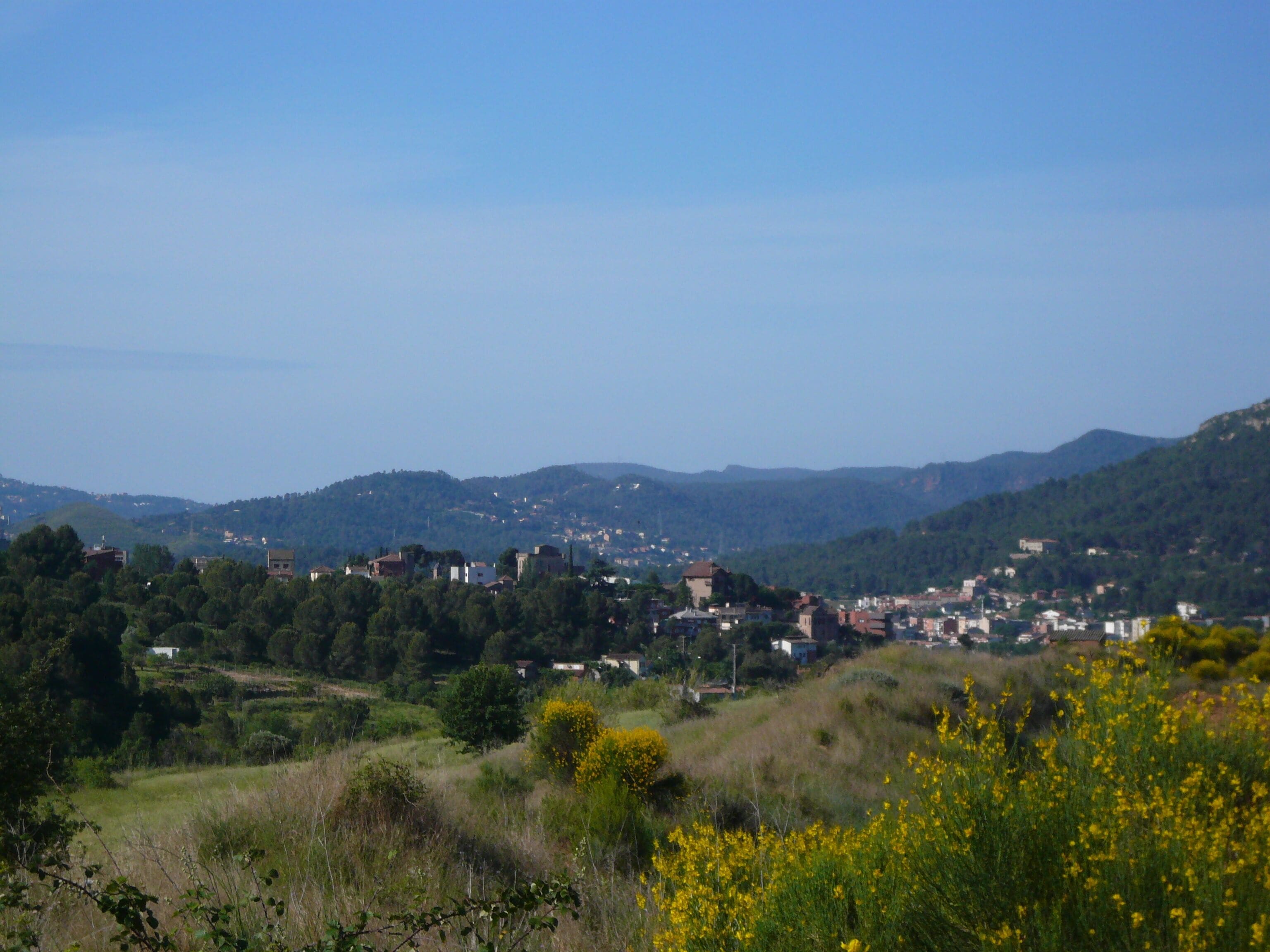 A town nestled in a valley with surrounding hills and greenery.