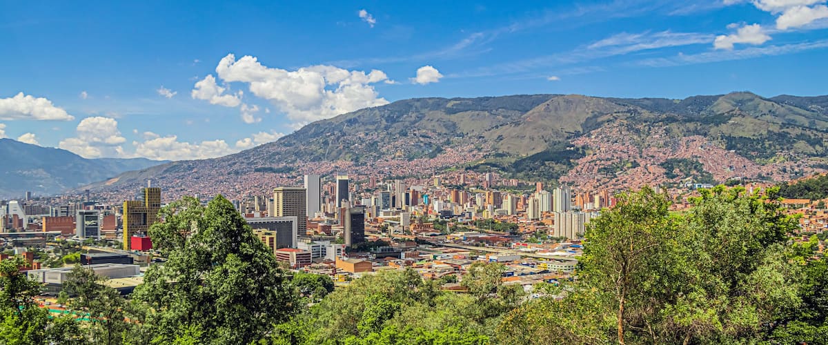 A cityscape with modern buildings and a mountainous backdrop.