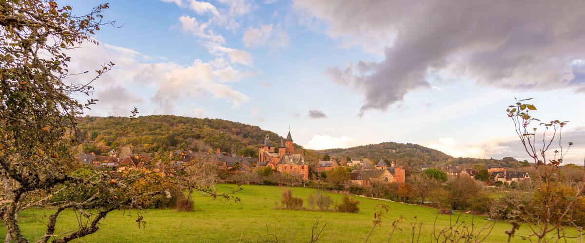 A historic castle on a hill, surrounded by green fields and trees.