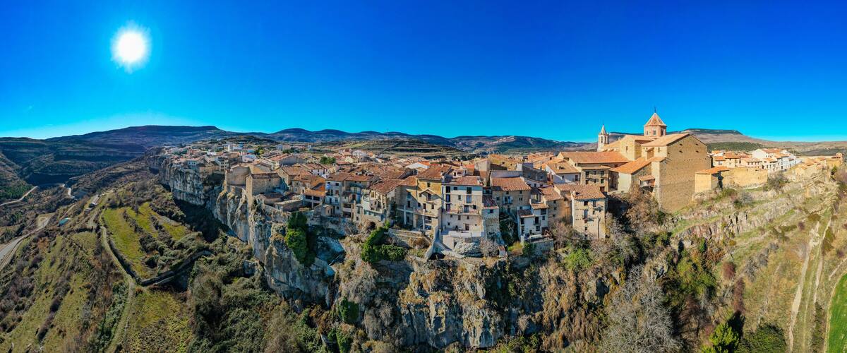 A mountainous village with terraced fields and historic buildings perched on a cliff.