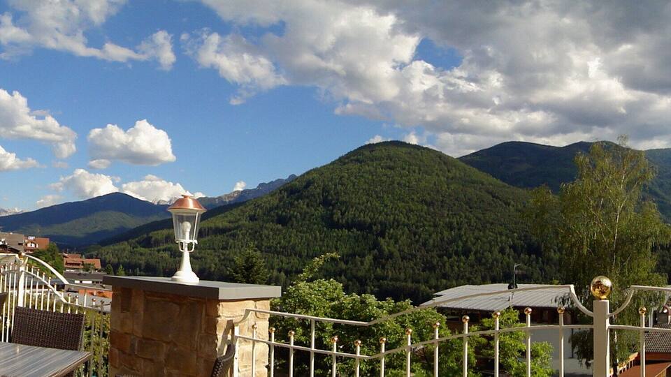 A mountainous landscape with a view of houses and a fence in the foreground.