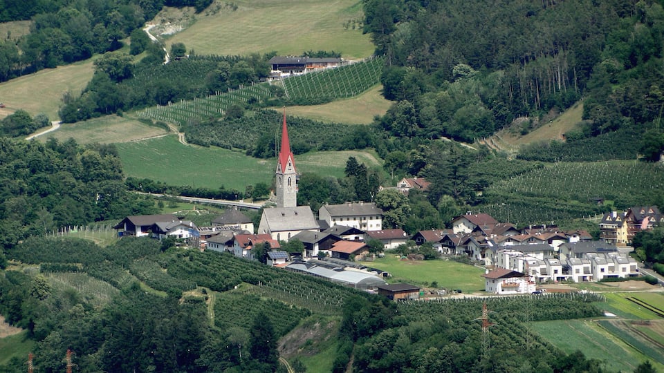 A village with a church, houses, and surrounding greenery.