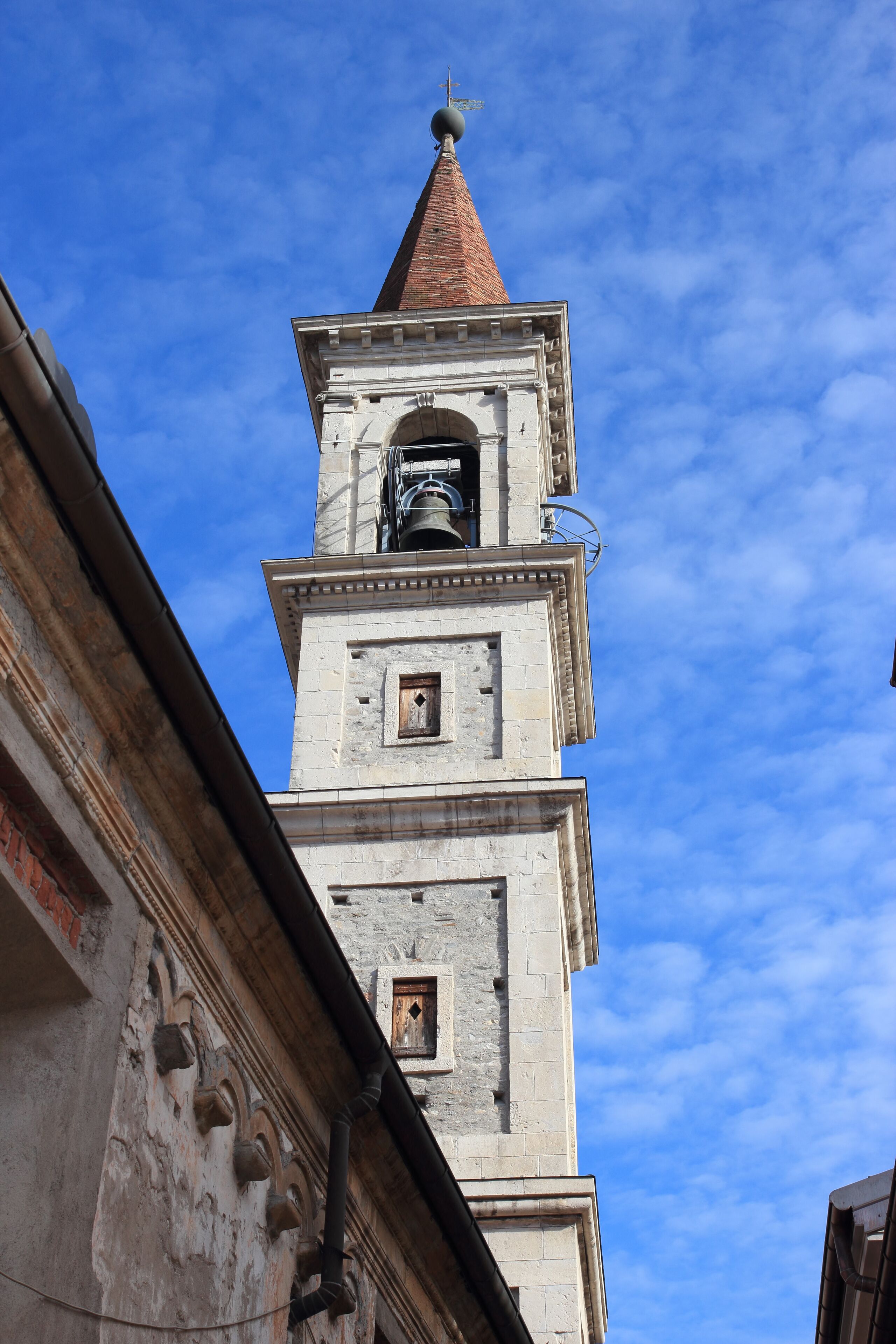 A historic tower with a clock and a spire against a blue sky.