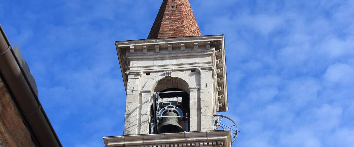 A historic tower with a clock and a spire against a blue sky.