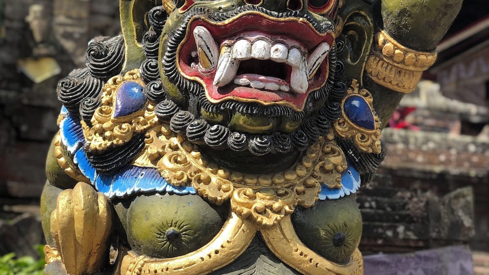 Eine detailreiche Statue mit strengem Gesichtsausdruck, verziert mit goldenen und blauen Verzierungen.