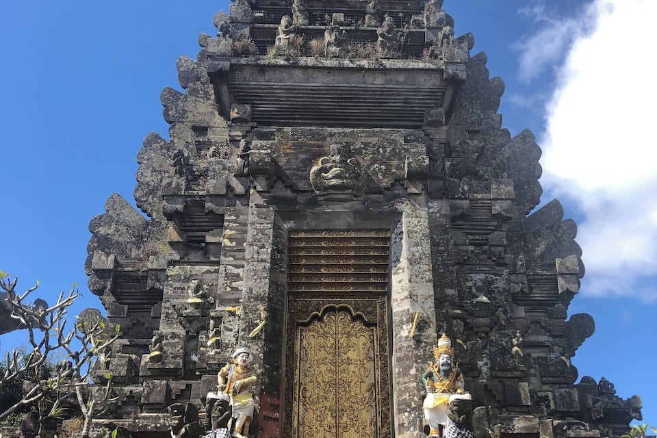 Een tempel met een gouden deur, stenen beelden en gedetailleerde gravures.
