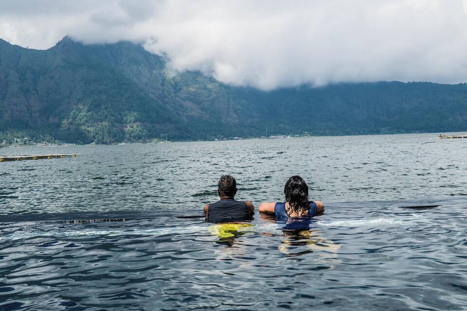 Two people in a lake with mountains in the background.