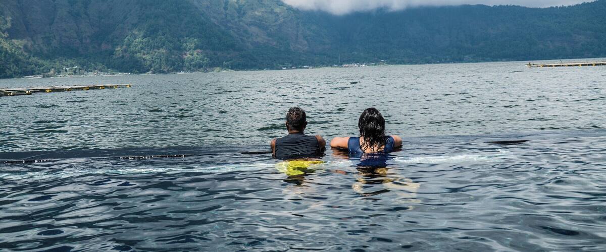 Two people in a lake with mountains in the background.