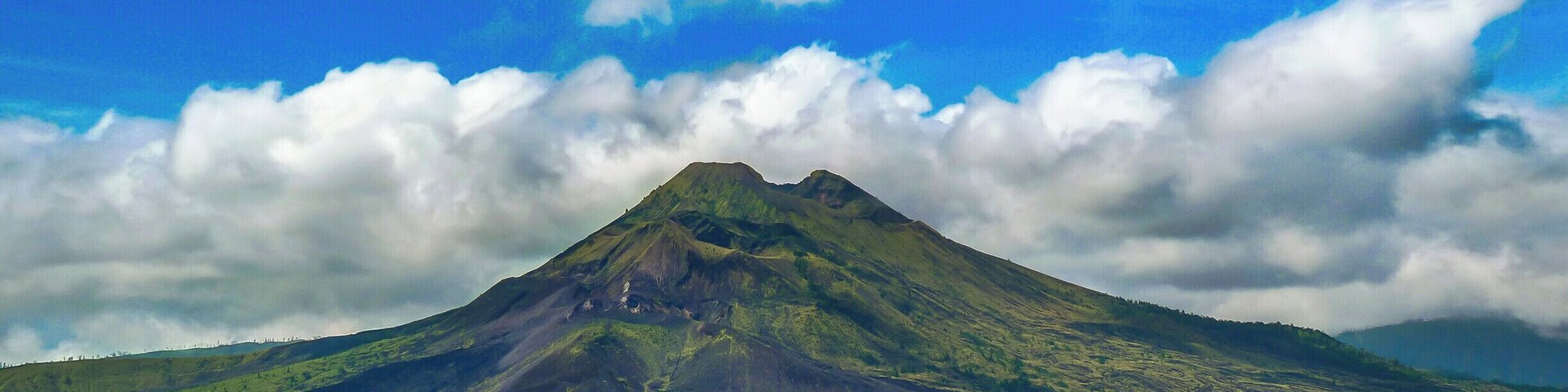 Mount Batur is the easiest climb of the three volcanos and provides spectacular views of Lake Batur and the ocean. It is also Bali’s most active volcano, so check whether it is safe to climb before you go.
Most people do the climb as an organized tour, but you can do it on your own if you prefer. If you decide to do the trek without a guide, be prepared to deal with local guides in Kintamani, the town where the trek starts, who have a reputation for being extremely pushy and doing almost anything to hinder people without a guide to reach the summit.
The track starts out as dirt path, but as it quickly gets steeper it also gets rockier and after a while vegetation is mainly limited to grasses growing among the rocks. Before reaching the summit, a small vender sells refreshments.
On the summit views reach as far as Mount Rinjani, and if you have a guide, he or she might cook you an egg boiled in volcanic steam before the descent.
Hight: 1717 meter
Difficulty: The trek is straight forward, so if you are in decent shape, you shouldn’t have many problems.
Trip length: It takes one to two hours to reach the summit and the same time to get down, but you should also include time to enjoy the views and explore the rim of the crater.