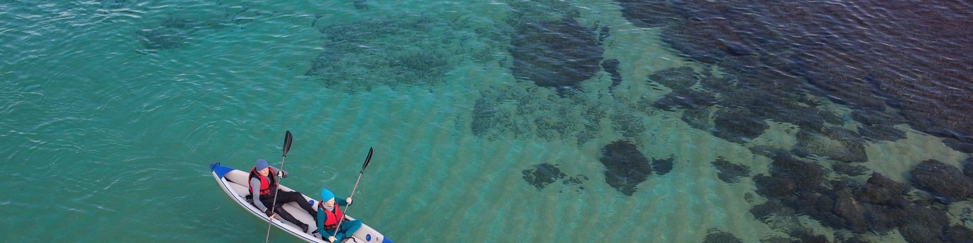 High angle view of mature couple kayaking in Mediterranean sea, Shavei Zion beach. The sea water is clear and sea bottom is visible.