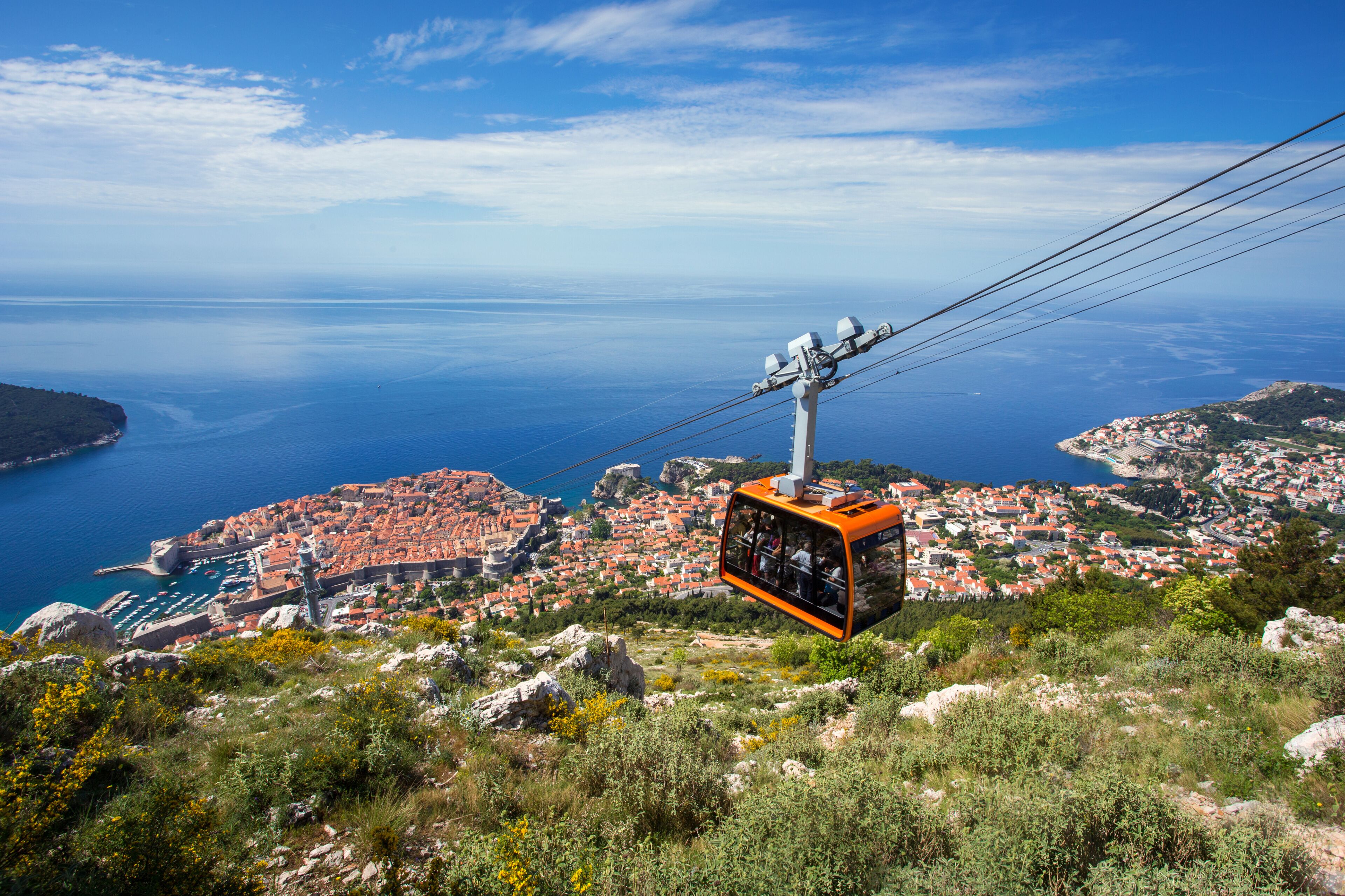 Un teleférico sobre un pueblo costero, con vistas despejadas al mar y colinas circundantes.