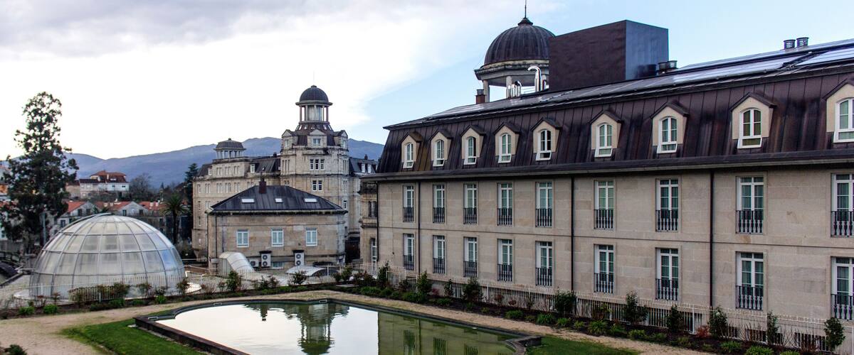 A historic building with a courtyard, a pond, and a dome structure.