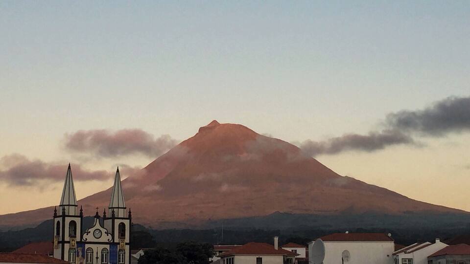 A church with two spires, a mountain, and a town in the foreground.