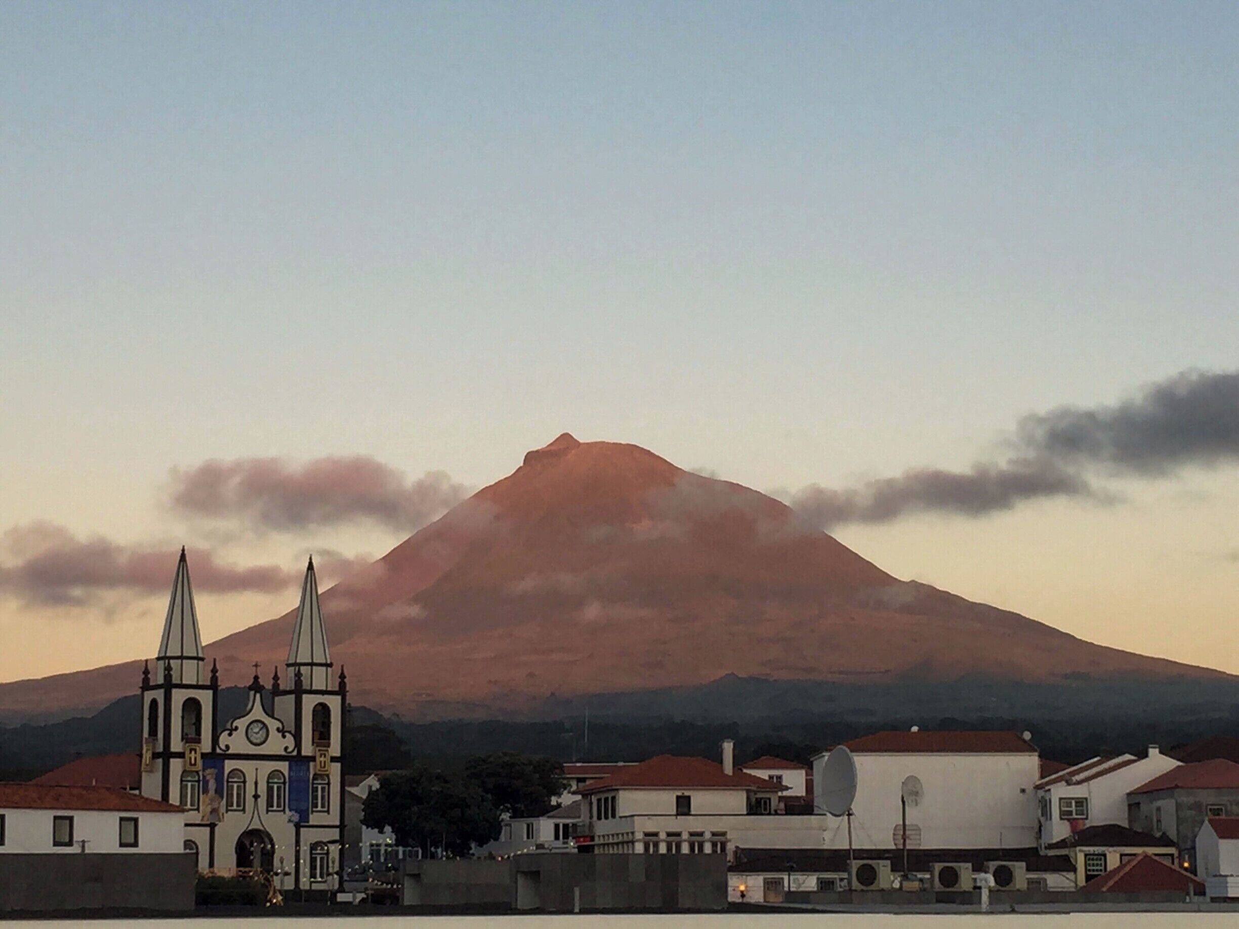 A church with two spires, a mountain, and a town in the foreground.