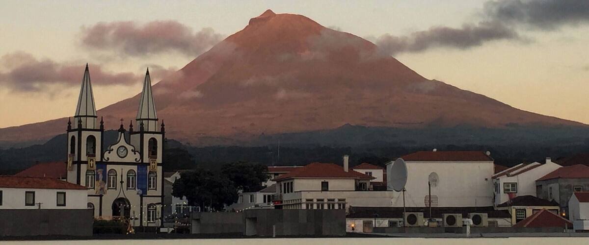 A church with two spires, a mountain, and a town in the foreground.