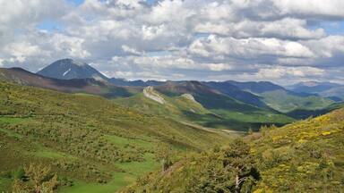 A mountainous landscape with a prominent peak, rolling hills, and a valley.