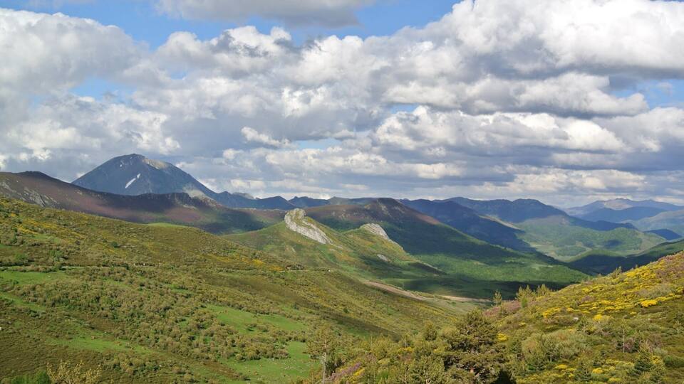 A mountainous landscape with a prominent peak, rolling hills, and a valley.