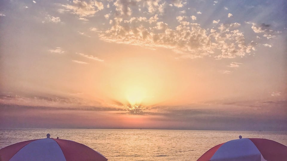 Scenic sunset over Adriatic sea beach in Durres, Albania and a silhouette of a boy running.
