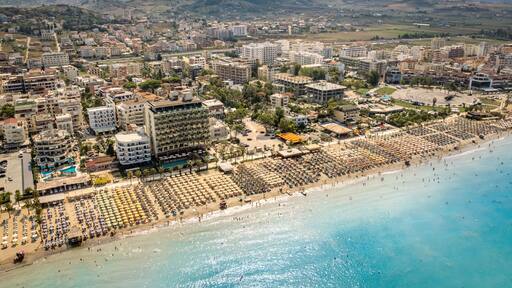 Golem, Durres, Albania - 22 august 2023: Aerial view to sandy beach full of umbrellas and people in summer season 2023