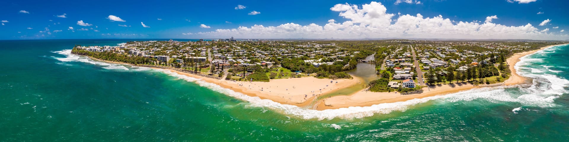 A coastal town with a beach, ocean, and clear blue sky.