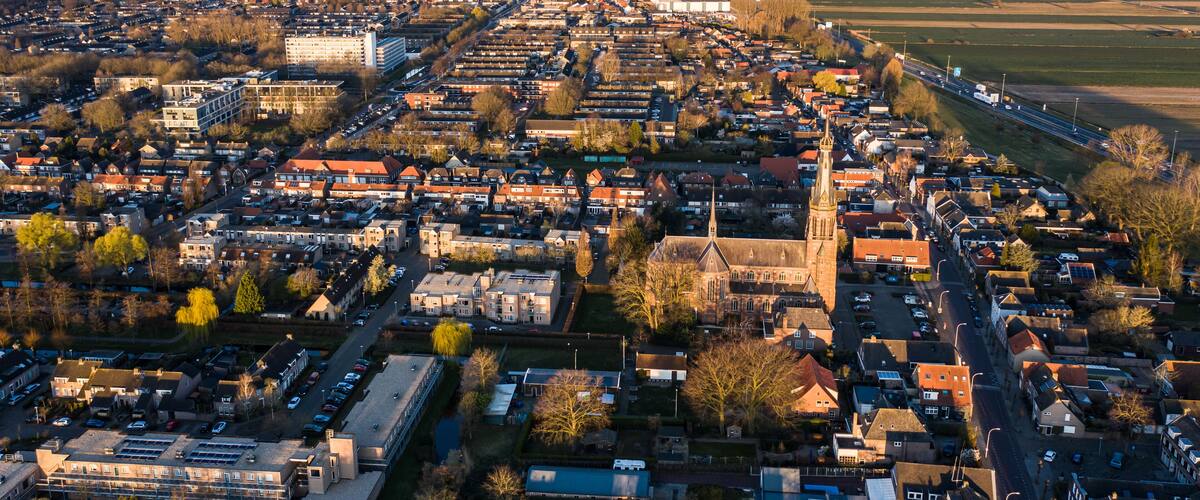 An aerial view of a city with dense residential areas, a prominent church, and a large industrial area.