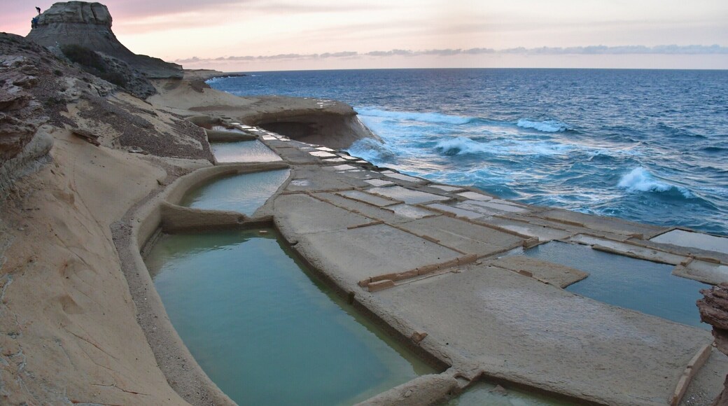On the north coast of Gozo, just past Qbajjar Bay west of Marsalforn, the coast is characterised by a chequerboard of rock-cut saltpans protruding into the sea. These 350-year-old salt pans, which stretch about 3km along the coast, are more than just scenic. They are part of the centuries-old Gozitan tradition of Sea-Salt production that has been passed down within certain families for many generations. During the summer months, locals can still be seen scraping up the crystals of salt. Once collected, the salt is stored and processed in the caves that have been carved into the coastal rock.