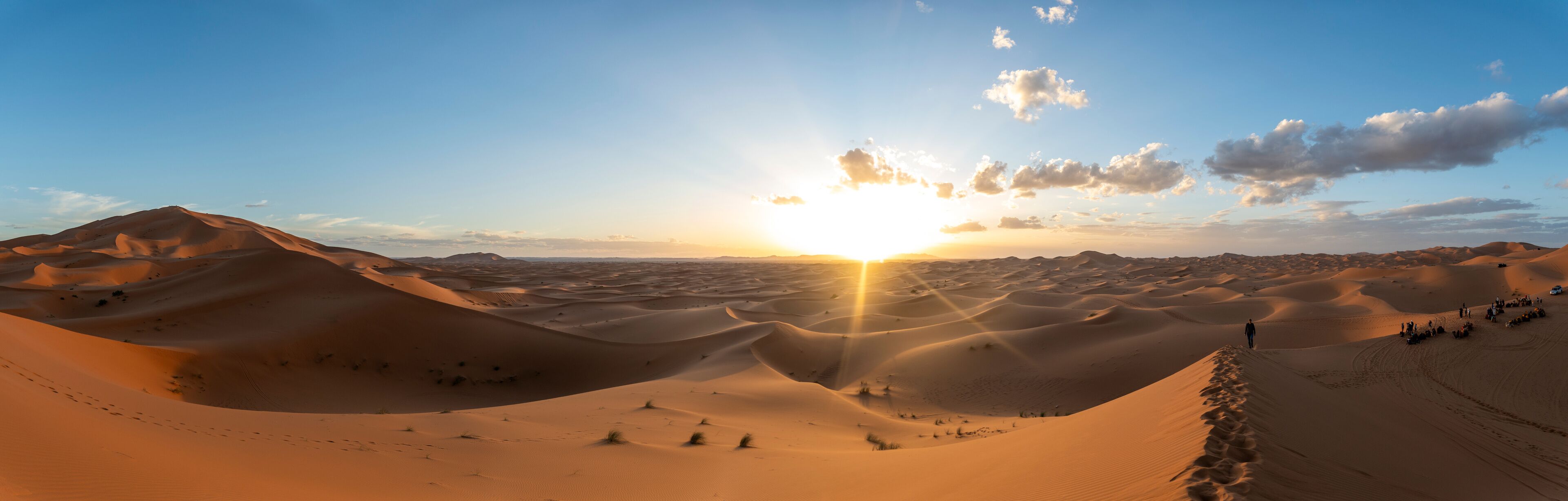 A desert landscape with sand dunes and a sunset.