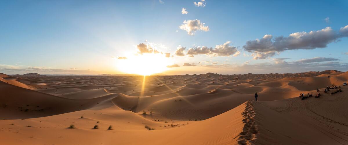 A desert landscape with sand dunes and a sunset.