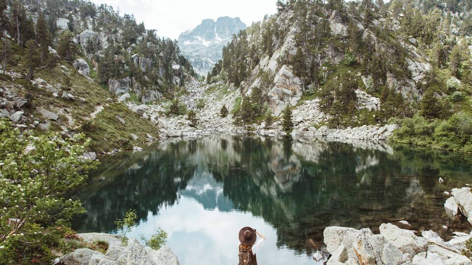 A mountainous landscape with a clear lake reflecting the surrounding trees and rocks.