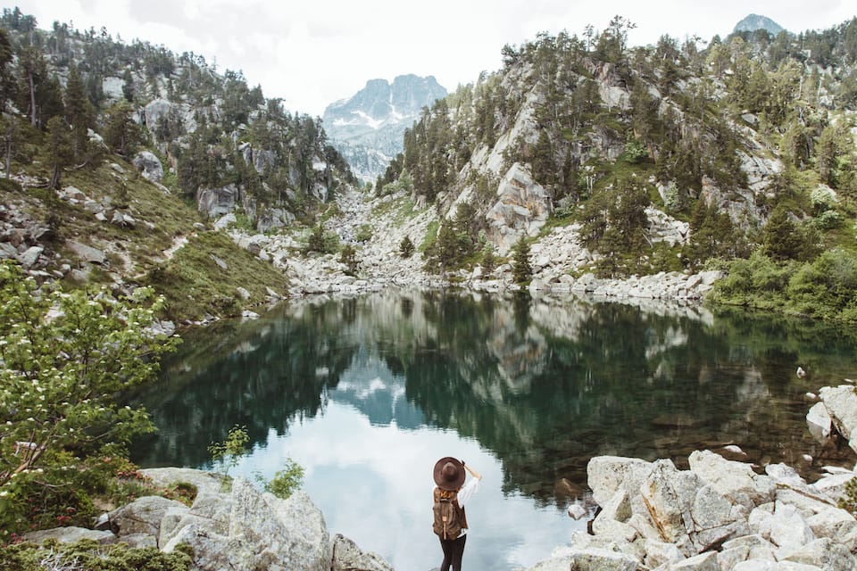 A mountainous landscape with a clear lake reflecting the surrounding trees and rocks.