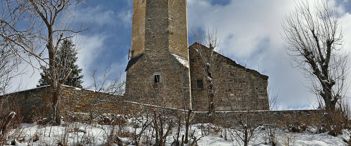 A stone church with a bell tower and a snow-covered landscape.