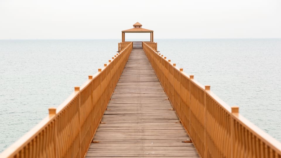 A wooden pier extending into calm waters, with a gazebo at the end.