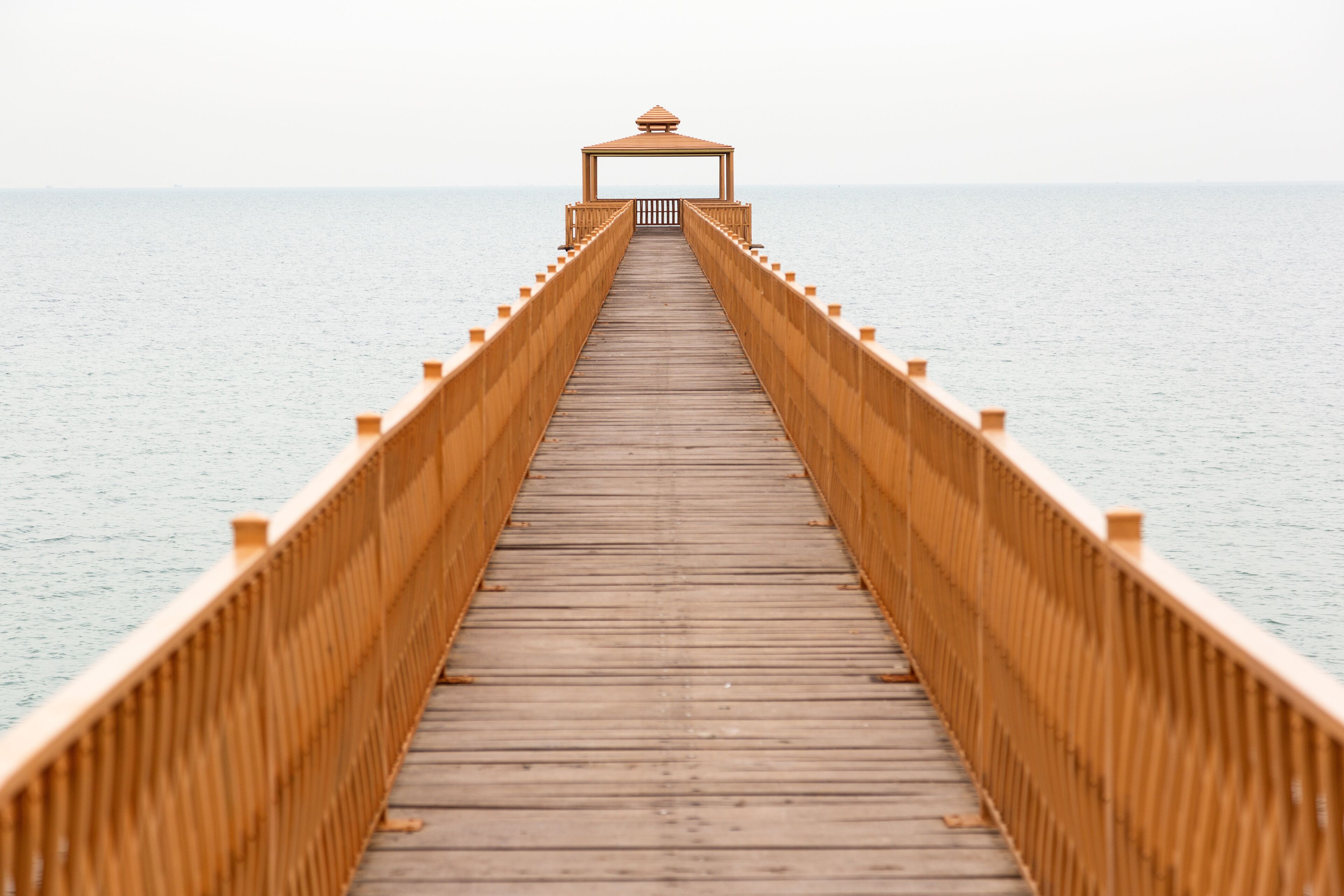 A wooden pier extending into calm waters, with a gazebo at the end.