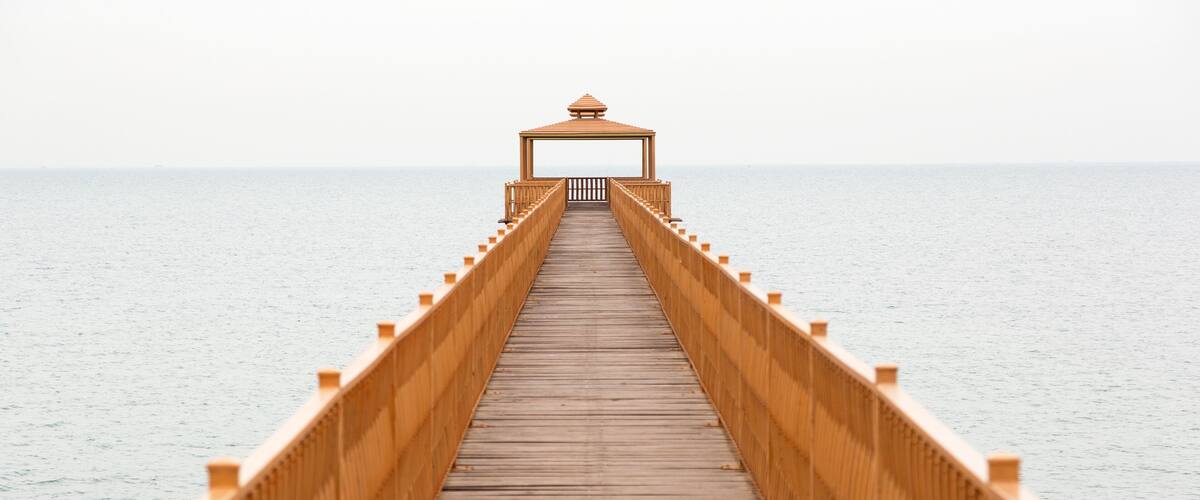 A wooden pier extending into calm waters, with a gazebo at the end.