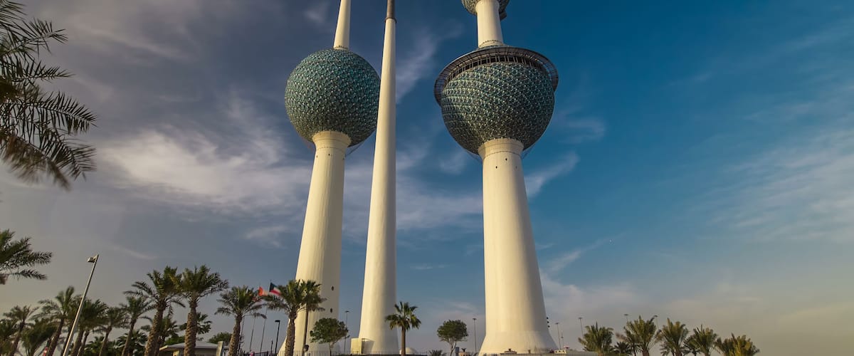 Three tall towers with spherical tops, surrounded by palm trees and a clear sky.