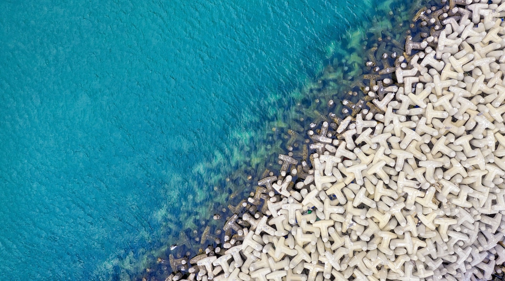 A turquoise sea with a white, rocky shoreline.
