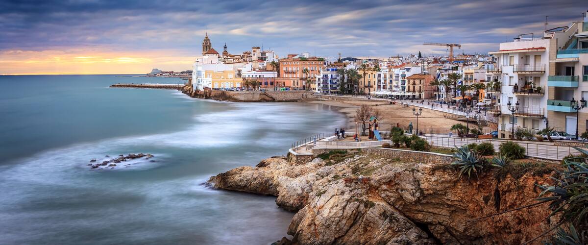 A coastal town with a rocky shoreline, a beach, and a mix of colorful buildings.