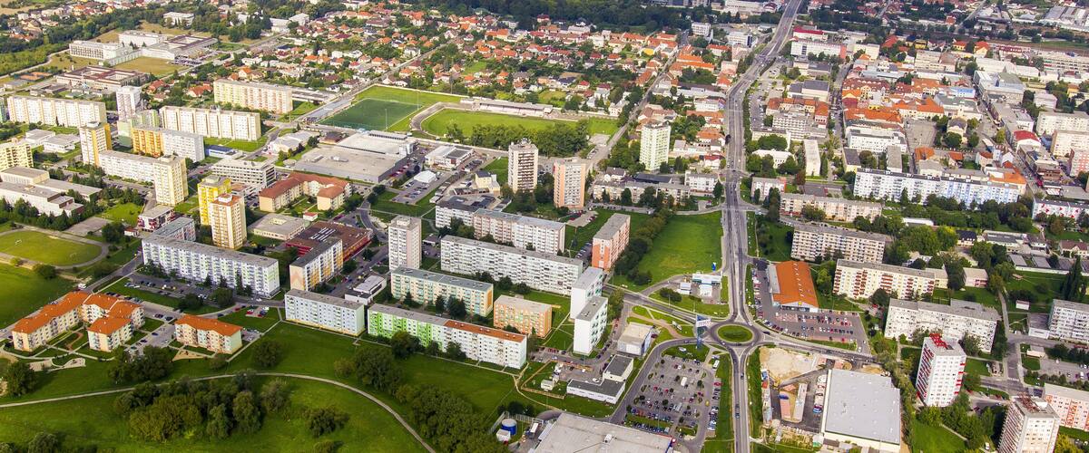Ilmakuva kaupungista, jossa näkyy asuinalueita, liikerakennuksia ja joki.