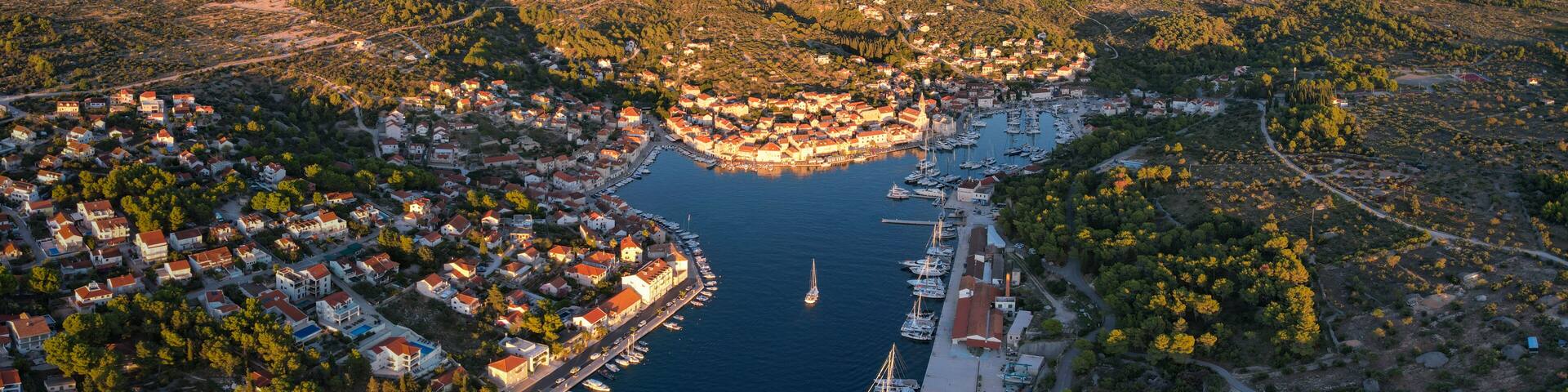 Aerial view of the sun-kissed town nestled along a tranquil bay, its terracotta roofs contrasting with the deep blue sea, Milna, Split-Dalmatia County, Croatia.