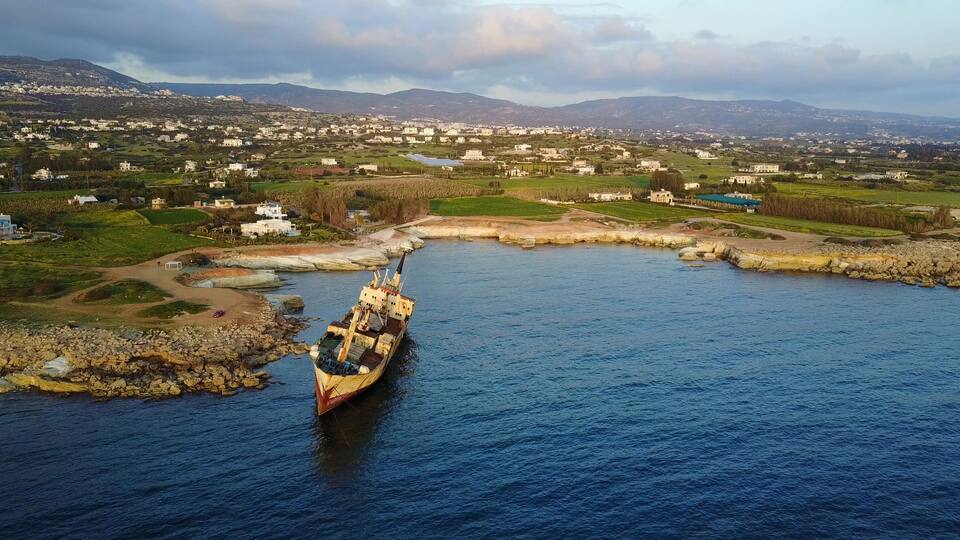 A coastal town with a harbor, boats, and a mountainous backdrop.