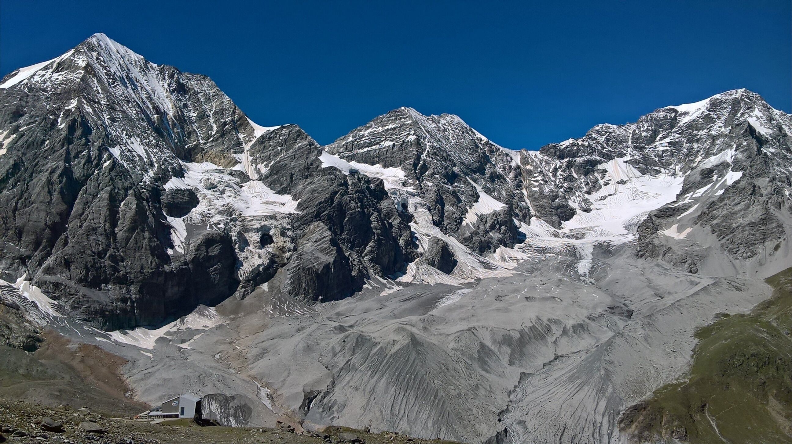 A rugged mountain range with snow-capped peaks and a clear blue sky.