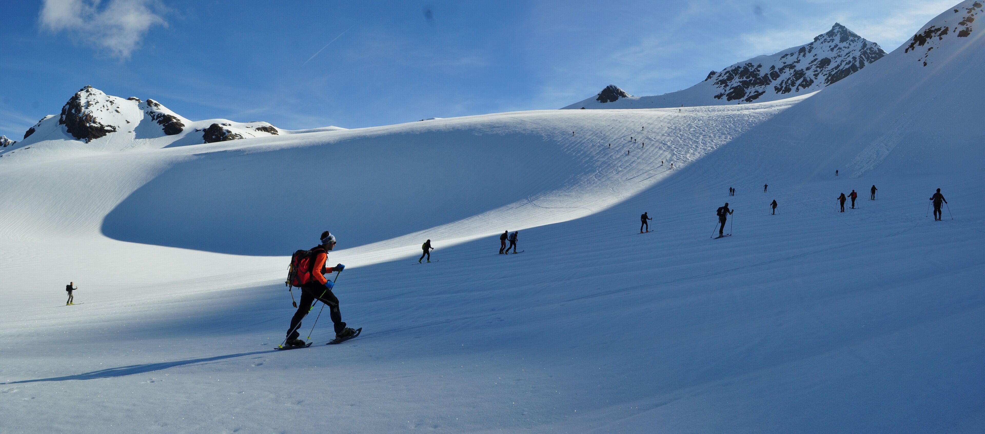 A snow-covered mountain slope with skiers descending.