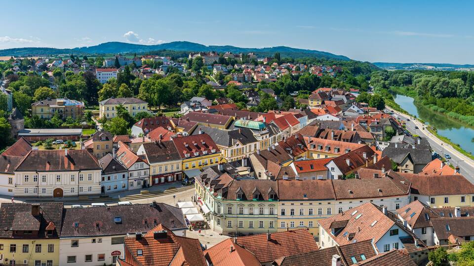 A town with historic buildings, a river, and a church spire.