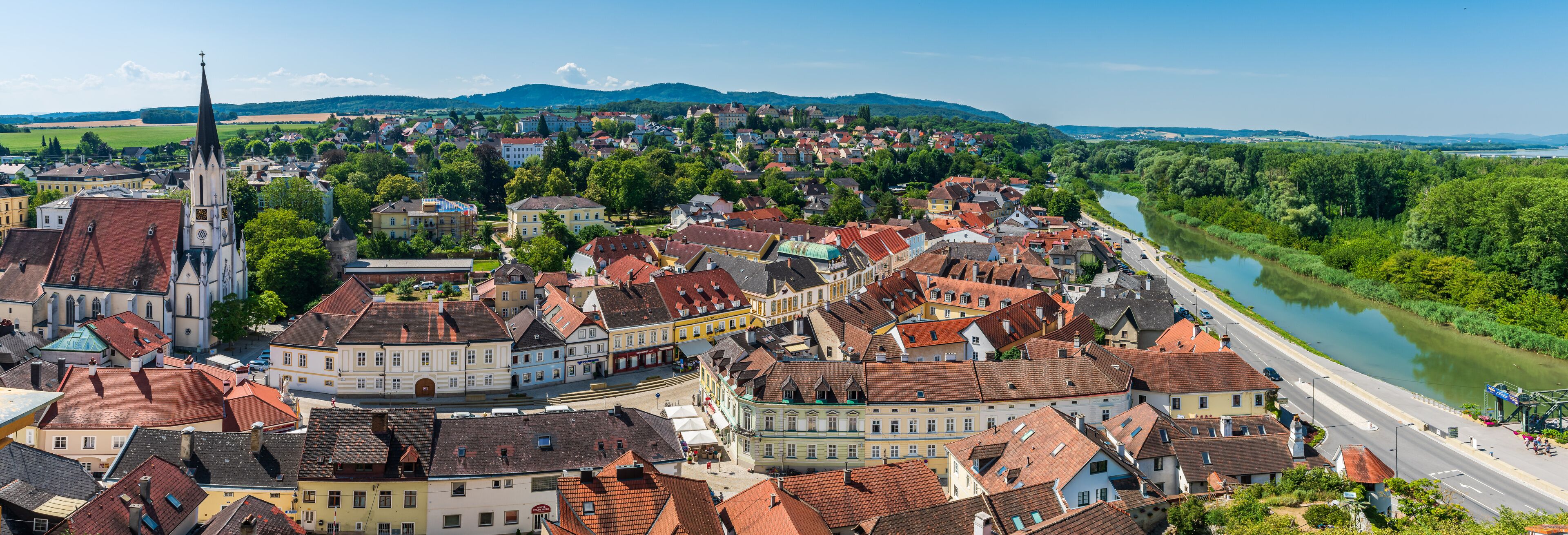 A town with historic buildings, a river, and a church spire.