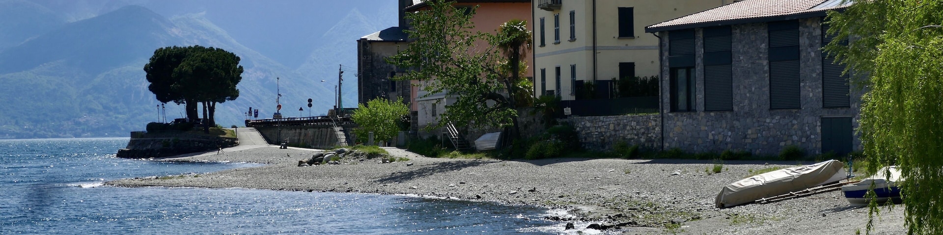 Un pueblo costero con edificios, una playa y montañas al fondo.