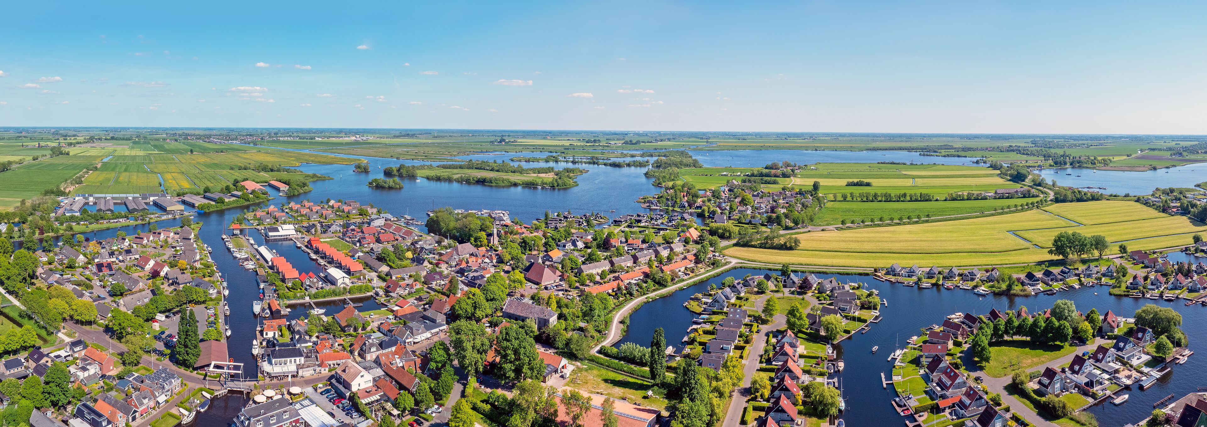 A riverside town with houses, boats, and fields.