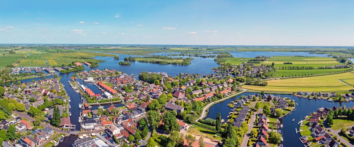 A riverside town with houses, boats, and fields.