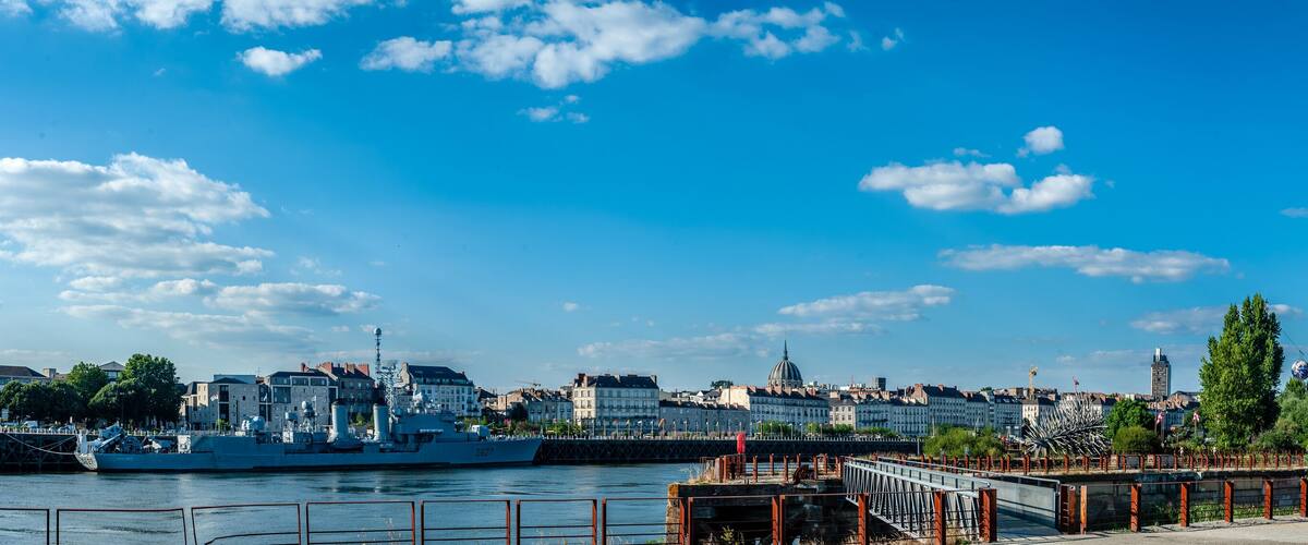 A river with a large yellow crane, a bridge, and a cityscape with historic buildings in the background.