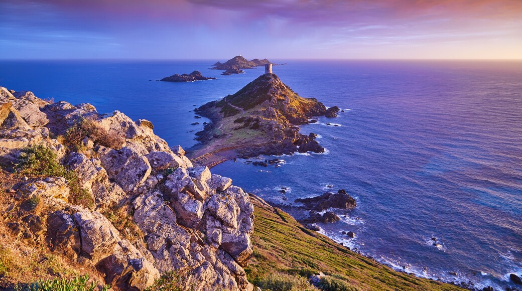 View of Pointe de la Parata on the west coast of Corsica France Europe. A ruined Genoese tower sits on top of the rocky promontory overlooking the archipelago of the Sanguinaires on the colored sunset